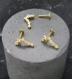 three pairs of gold - plated earrings sitting on top of a cement slab,