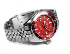 The OCEAN 200 is a watch inspired by the Diver watches of the 70s. The 01 is an automatic diving watch with a Swiss STP1-11 mechanical movement with date. Presented with a stainless steel case and bracelet. It features a 120-click unidirectional red aluminum bezel. The red dial features luminous indices. The hour, minute and second hands are filled with Super-Luminova. Water resistant to 20 ATM / 200 m. Designed and assembled in Spain The OCEAN 200 series is assembled in Mallorca (Spain) by a tr Red Watch With Date Indicator And Round Dial, Classic Red Watch Accessories With Date Indicator, Diving Watch, Mallorca Spain, Mechanical Movement, Dive Watches, Wristwatch Men, Swiss Made, Wrist Watches