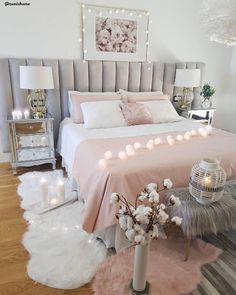 a bedroom decorated in pink and white with lights on the headboard, bedding, rugs and pillows