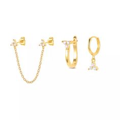 three pairs of gold hoop earrings with white stones on each ear and a chain attached to them