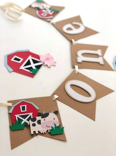 paper cutouts are hanging from the side of a table with farm animals on it