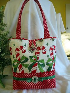 a red and white bag with candy canes on it sitting next to a christmas tree