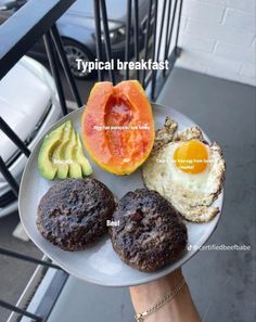 a person holding a plate with eggs, avocado and other foods on it