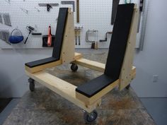 two black chairs sitting on top of a wooden cart in a garage next to tools