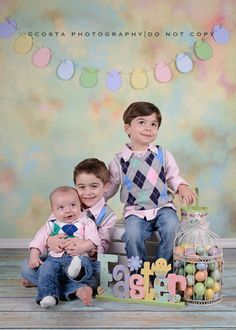 two young boys sitting next to each other in front of an easter sign and eggs