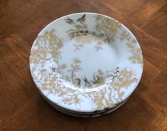 a white and gold plate sitting on top of a wooden table