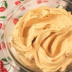 a glass bowl filled with peanut butter on top of a floral tablecloth covered table