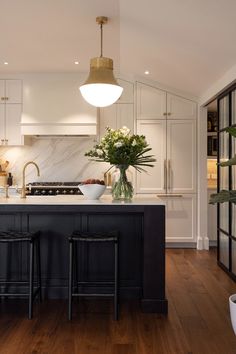 a kitchen with two stools next to an island in front of a sink and stove