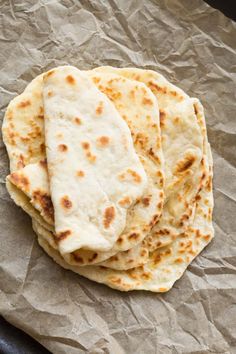 four flat breads are sitting on top of some waxed paper and there is no image here to provide a caption for