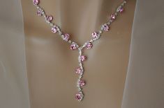 a necklace with pink and white flowers is on display in front of a mannequin