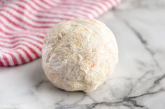 a ball of white bread sitting on top of a marble counter next to a red and white towel