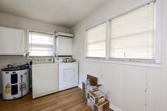 an empty kitchen with white appliances and wood floors