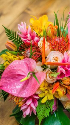 a bouquet of flowers is sitting on a table with green leaves and pink lilies