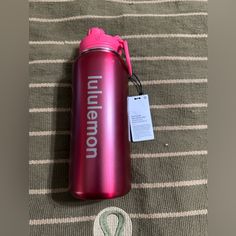 a red water bottle sitting on top of a bed next to a tag that says utensino