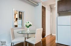 a white refrigerator freezer sitting inside of a kitchen next to a dining room table