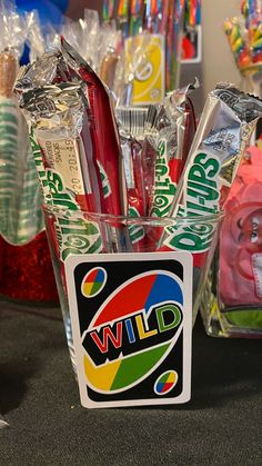 a cup filled with candy and toothbrushes sitting on top of a table next to other items