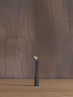 a small black object sitting on top of a wooden table next to a brown wall