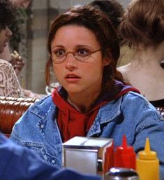 a woman with glasses sitting at a table in front of two other women and one man