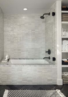 a bathroom with white tile and black accents on the walls, along with a bathtub