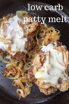 two hamburger patties covered in gravy and cheese on a skillet pan