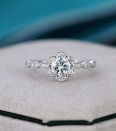 a white gold engagement ring with an intricate flower design on the band and center stone