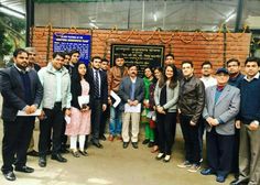 a group of people standing next to each other in front of a brick wall with writing on it