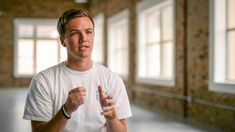 a man in a white t - shirt is giving the thumbs up