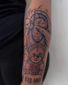 a person with a tattoo on their arm holding a teddy bear in the shape of a heart