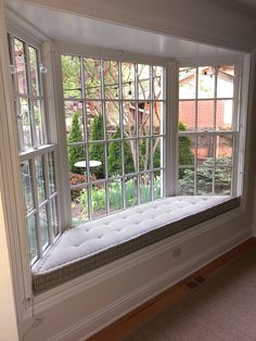 an empty window seat in the corner of a room with large windows on both sides