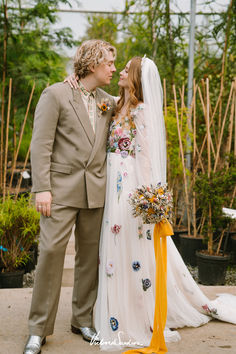 a bride and groom standing next to each other in front of some potted plants