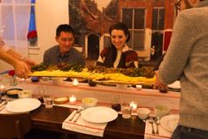 a group of people standing around a table with food on it and candles in front of them