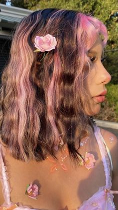 a woman with pink hair and flowers in her hair is looking off into the distance