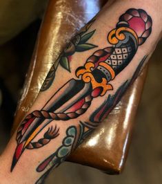 a person with a tattoo on their arm holding a knife and some other things in the background