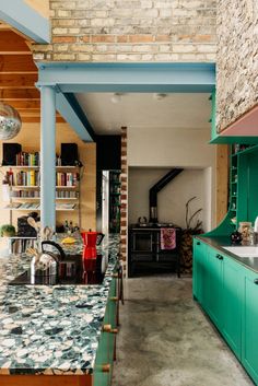 a kitchen with green cabinets and marble counter tops in an old brick building that has been converted into a loft