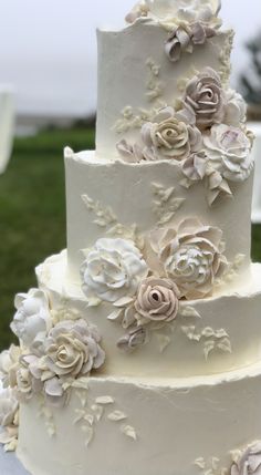 a three tiered cake with flowers on the top and bottom is decorated in white frosting