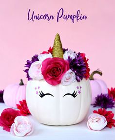 a white pumpkin decorated with flowers and a unicorn's head