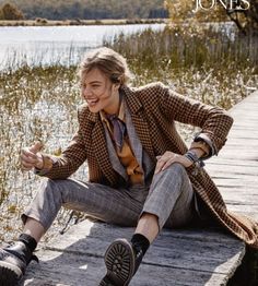 a man is sitting on a dock with his foot in the air and smiling at the camera