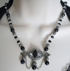 "This beautiful necklace has black glass beads, seed beads, black glass pearl beads, clear faceted beads, silver plated bead caps, metal chain, silver plated filigree beads and a silver plated filigree pendant with faceted glass setting and rhinestones. 18\" long. Toggle clasp." Gothic Silver Jewelry With Black Beads, Gothic Beaded Jewelry For Evening, Elegant Metal Necklace With Faceted Beads, Antique Beaded Evening Necklaces, Antique Beaded Necklaces For Evening, Antique Beaded Necklace For Evening, Antique Beaded Jewelry For Evening, Antique Beaded Evening Necklace, Bohemian Black Beaded Evening Jewelry