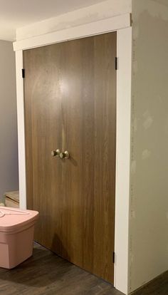 a pink box sitting on the floor next to a wooden door in an empty room