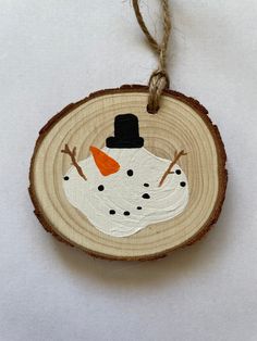 a wood slice with a snowman ornament hanging from it's side