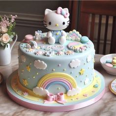 a hello kitty birthday cake with pastel colors and rainbows on the bottom tier