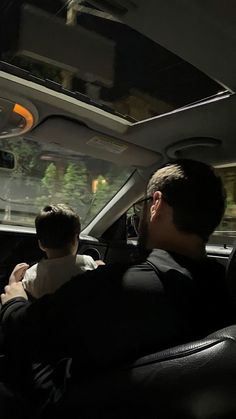 two people sitting in the back seat of a car, one is holding a baby