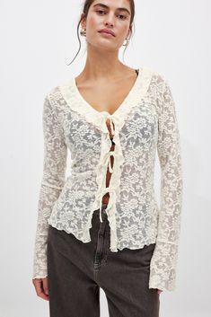 This top features a relaxed fit and a sheer stretchy material with a soft textured feel and a floral design. It has ruffle details at the front and trumpet sleeves. Our top has a self tie closure down the front. Luxury Sheer Romantic Tops, Cheap Feminine Tops For Layering, White Lace Shirt, Trumpet Sleeves, Low Waist Jeans, Floral Lace Tops, Trumpet Sleeve, Ruffled Top, Tie Front Blouse