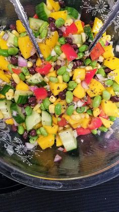 mango - edamame salad in a bowl with two serving spoons