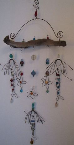 a wooden branch with beads hanging from it's sides and an insect mobile attached to it