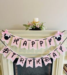 a happy birthday banner with minnie mouse on it next to a fire place in a living room