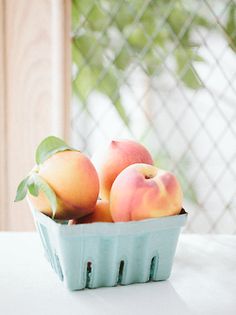 a blue basket filled with peaches on top of a table