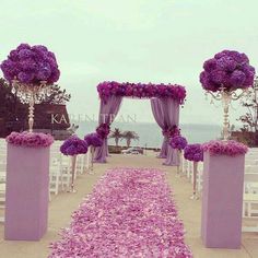 an outdoor ceremony setup with purple flowers on the aisle