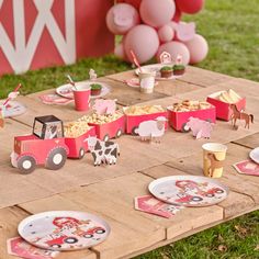 a table set up for a farm birthday party with pink and white plates, paper napkins, and decorations