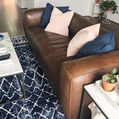 a brown leather couch sitting on top of a blue rug